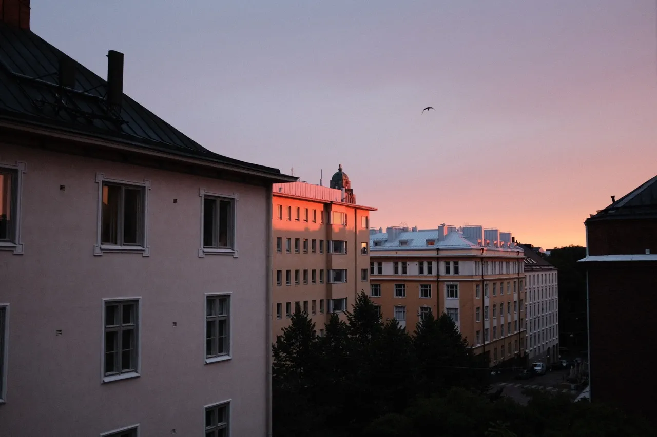 A photo of a sunset coloring some roofs.